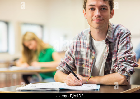 Smiling student with others writing notes in classroom Stock Photo