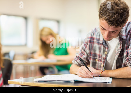 Student with others writing notes in classroom Stock Photo