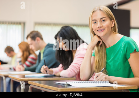 Female student with others writing notes in classroom Stock Photo