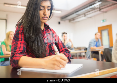 Female student with others writing notes in classroom Stock Photo