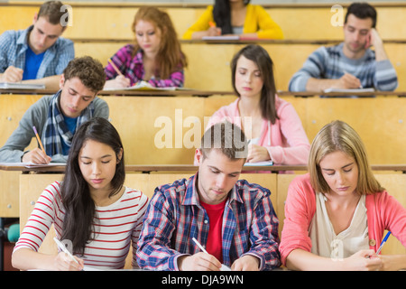 Students sitting at the lecture hall while writing Stock Photo