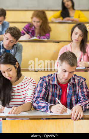 Students sitting at the lecture hall while writing Stock Photo