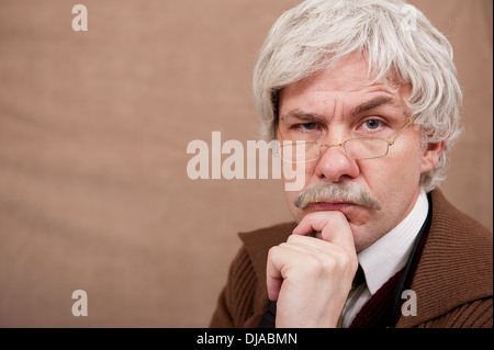 Pensive grey haired old man with his hand against his chin. Stock Photo