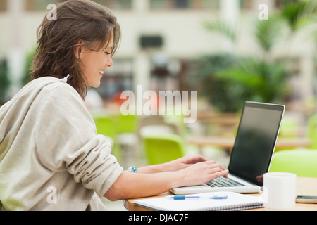 Student using laptop at cafeteria table Stock Photo