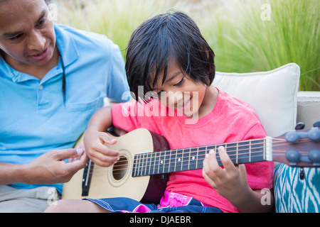 Father teaching son to play guitar outdoors Stock Photo