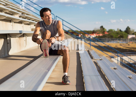 Hispanic athlete resting on bleachers Stock Photo