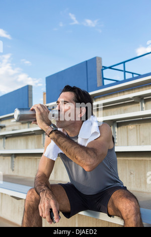 Hispanic athlete resting on bleachers Stock Photo