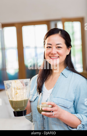 Mixed race woman drinking green smoothie Stock Photo