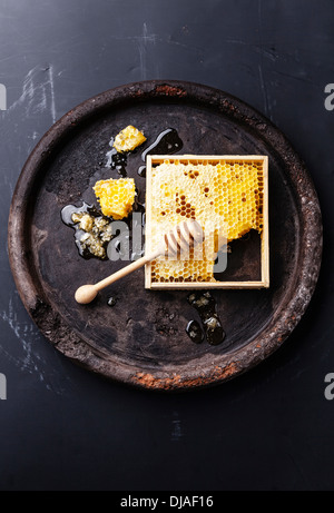 Honeycomb with wooden honey dipper on black textured background Stock Photo