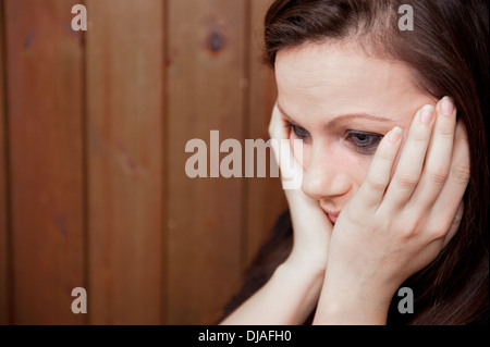 Upset young woman with her eye make-up running down her face from crying and her head in her hands. Stock Photo