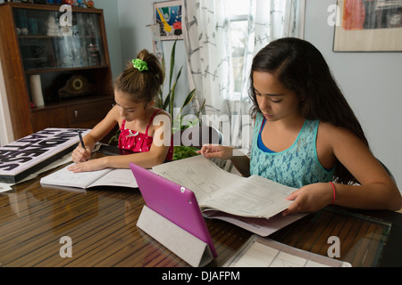 Mixed race sisters doing homework at table Stock Photo
