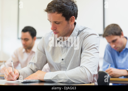 Mature students taking notes in lecture Stock Photo