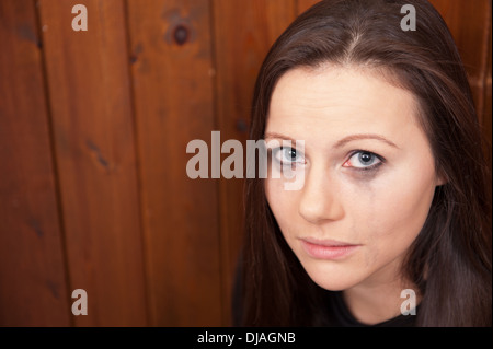 Upset looking young woman with her eye make-up running down her face. Maybe a victim of domestic violence, bullying or abuse. Stock Photo