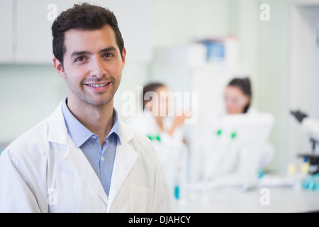 Smiling researcher with colleagues in background at lab Stock Photo