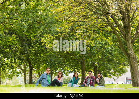 College students sitting on grass in park Stock Photo