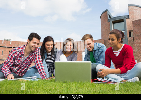 Students using laptop in lawn against college building Stock Photo