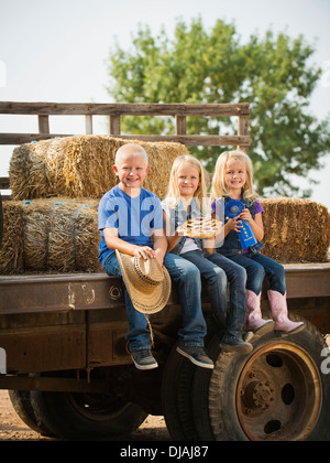Caucasian children sitting on truck on farm Stock Photo