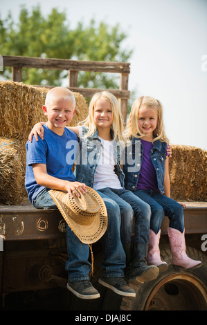 Caucasian children sitting on truck on farm