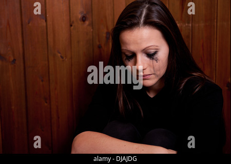 Upset young woman with her eye make-up running down her face from crying. Stock Photo