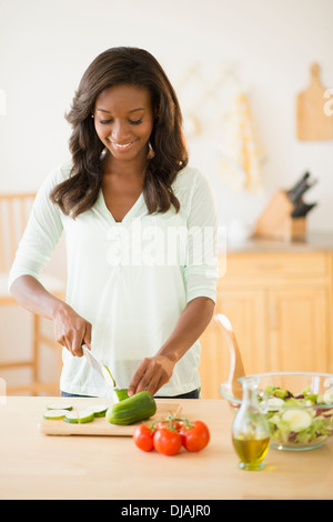 Black woman chopping vegetables in kitchen Stock Photo