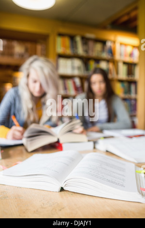 Two blurred students writing notes at library desk Stock Photo
