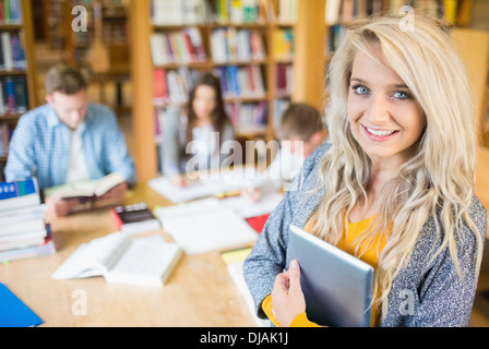 Female student with others in background at library Stock Photo