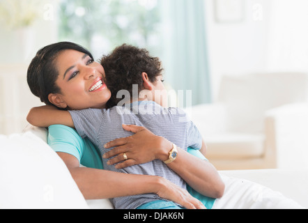 Mother hugging son on sofa Stock Photo