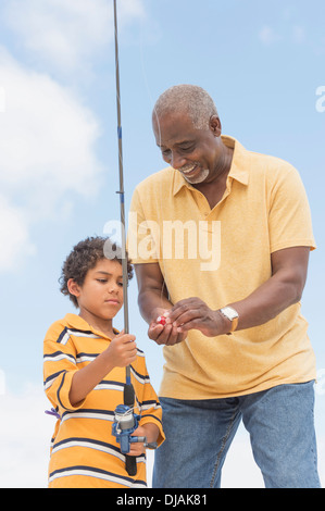 Older man teaching grandson to fish Stock Photo