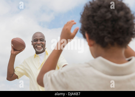 Boy playing catch with grandfather outdoors Stock Photo