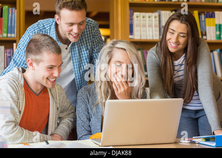 Happy students using laptop at desk in library Stock Photo - Alamy