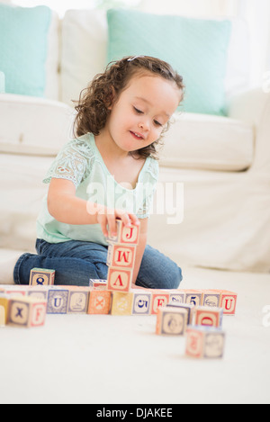 Mixed race girl playing with wooden blocks Stock Photo