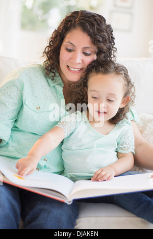 Mixed race mother reading with daughter Stock Photo