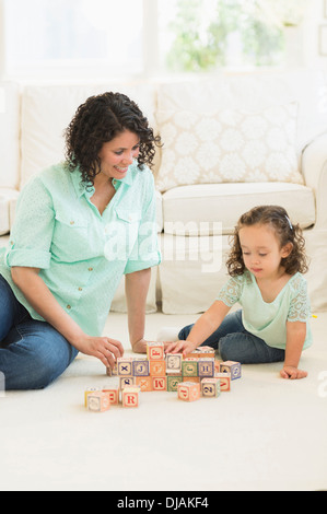 Mixed race mother and daughter playing with wooden blocks Stock Photo