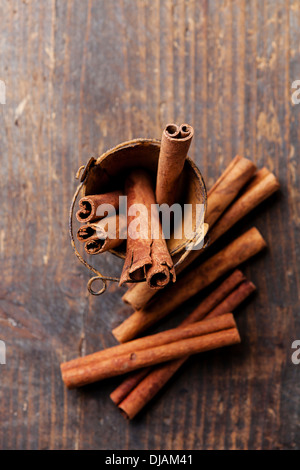 Cinnamon sticks in bucket on wooden background Stock Photo