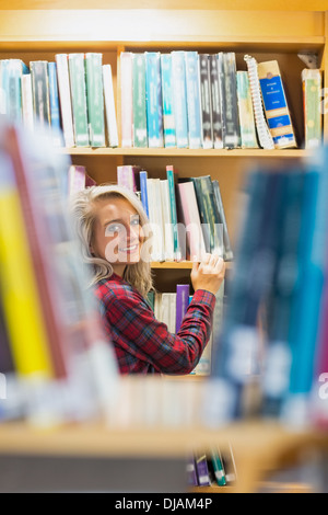 Smiling female amid bookshelves in the library Stock Photo