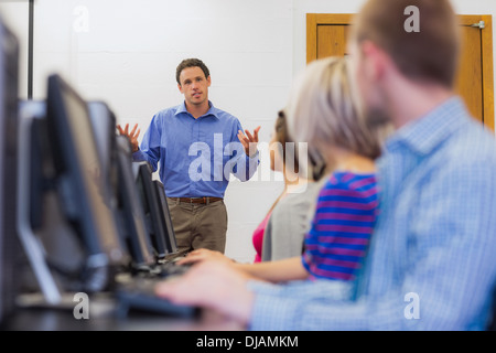 Teacher explaining to students in computer room Stock Photo