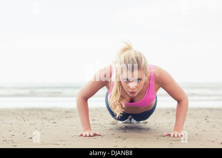 Beautiful woman doing push ups on beach Stock Photo