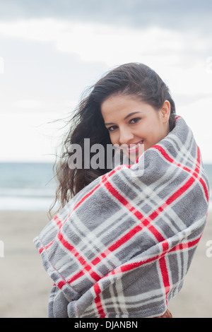 Portrait of woman covered with blanket at beach Stock Photo