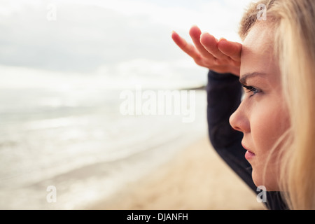 Side view of a beautiful blond shielding eyes at beach Stock Photo