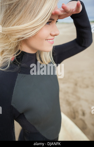 Side view of beautiful blond shielding eyes at beach Stock Photo