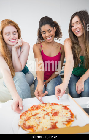 Happy female friends eating pizza at home Stock Photo