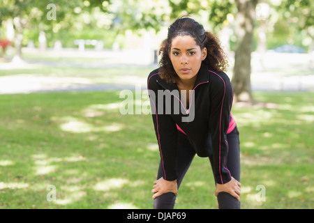 Tired young woman taking a break while jogging in park Stock Photo