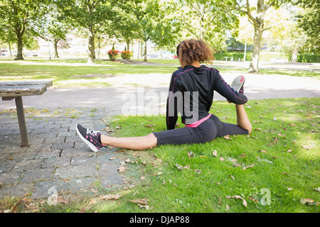 Flexible young woman doing the splits exercise in park Stock Photo