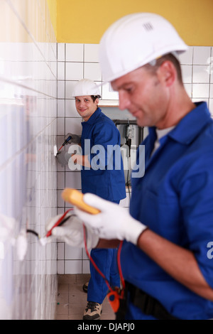 Electricians working in a tiled room Stock Photo