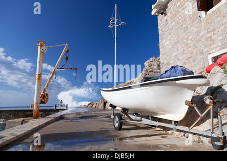 White fishing boat and small crane. Embankment of Petrovac town, Montenegro Stock Photo