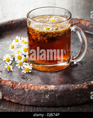 Chamomile tea with chamomile flowers on dark background Stock Photo