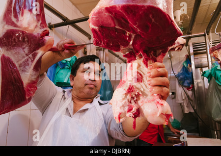 Butcher at work slicing meat at his shop in Deira. Dubai, UAE. Stock Photo