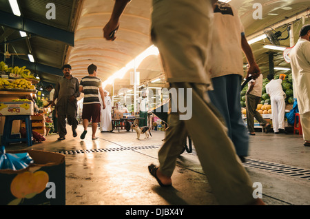 Arab men walking along one of the corridors at Deira's Fruit and Vegetable Market during sunrise. Dubai, UAE. Stock Photo