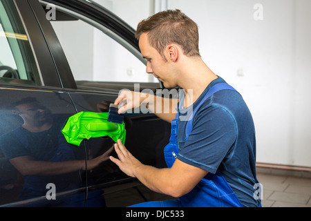 Car wrapping specialist wraps a car door handle with adhesive foil or film Stock Photo