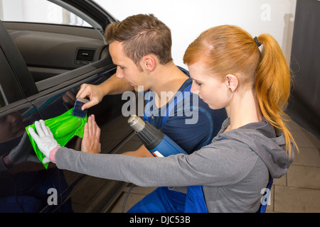 car wrapping professional wrapping car door handle in colorful foil or film using a squeegee Stock Photo